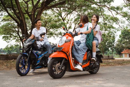 Photo for Two naughty high school girls riding motorbikes teasing boy students on the street - Royalty Free Image