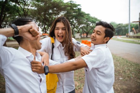 Téléchargez les photos : Deux lycéens en uniforme se battant réconciliés par une fille dans la cour - en image libre de droit