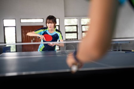 Photo for Close up of female athlete preparing to serve against opponent at ping pong table - Royalty Free Image