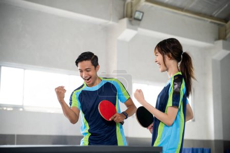 Photo for Two ping pong players compete with fists while scoring at the ping pong table - Royalty Free Image