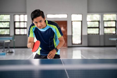 Photo for Male ping pong player in a position ready to receive the ball from the opponent in a ping pong match - Royalty Free Image