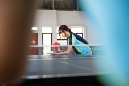 Photo for Female athlete holding paddle and ball while serving in table tennis - Royalty Free Image