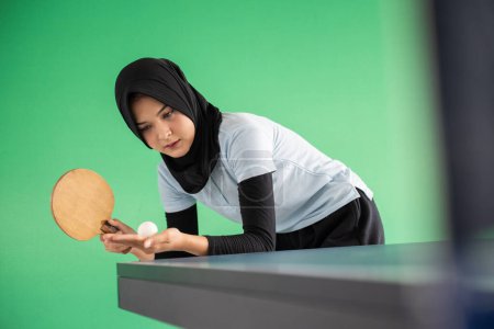 Photo for Young asian girl in hijab playing table tennis on green background - Royalty Free Image