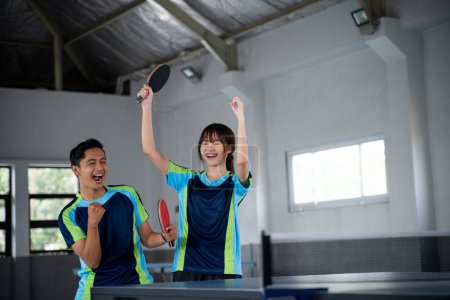 Photo for Male and female asian ping pong players happy to score in ping pong match - Royalty Free Image