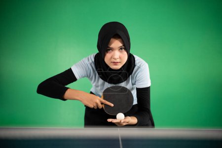 Photo for Female athlete in hijab preparing to serve while playing ping pong - Royalty Free Image