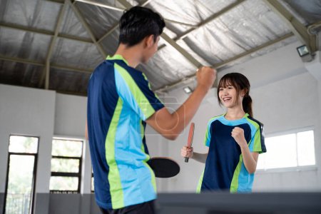 Photo for Two asian ping pong players excited while competing at the ping pong table - Royalty Free Image