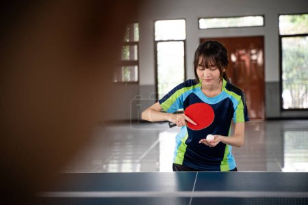 Photo for Female athlete holding ball serving against opponent at ping pong table - Royalty Free Image