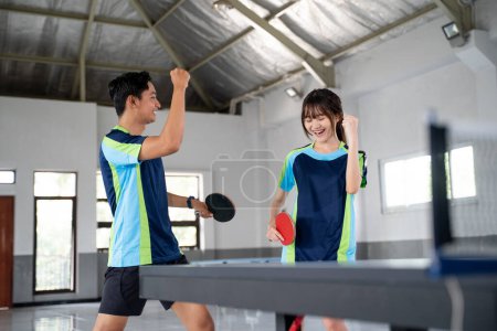 Photo for Two ping pong players encourage each other while competing at the ping pong table - Royalty Free Image