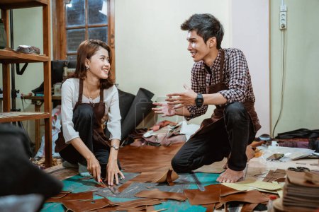 Téléchargez les photos : Homme artisan discute avec femme artisan avant de couper le cuir dans l'atelier - en image libre de droit