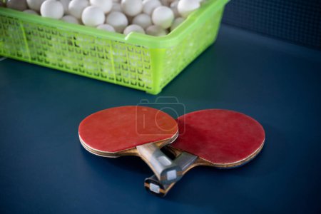 Téléchargez les photos : Deux pagaies en caoutchouc avec un panier de boules sur une table de ping-pong - en image libre de droit