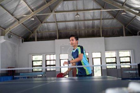 Photo for Asian male athlete ready to receive ball in ping pong match - Royalty Free Image