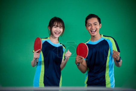 Photo for Asian male and female players with fists while winning ping pong match - Royalty Free Image