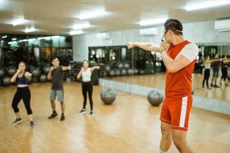 Photo for Male instructor doing punching moves followed by several people during practice - Royalty Free Image