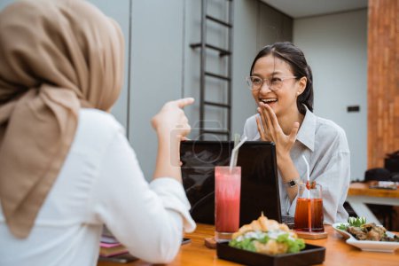 Foto de Two girls enjoying a meal while discussing college assignments when they meet in a cafe - Imagen libre de derechos