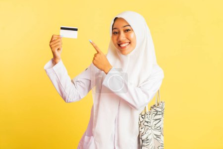 Téléchargez les photos : Indonesian veiled high school girl showing card with pointing finger on isolated background - en image libre de droit