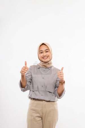 Téléchargez les photos : A beautiful woman with hijab standing facing forward with thumbs up and smiling on the white background - en image libre de droit