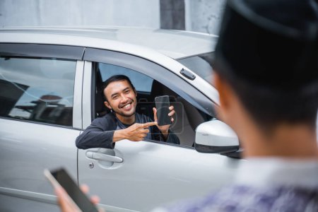 Foto de Hombre en el coche que muestra el teléfono celular al hombre con la tapa y la celebración del teléfono celular fuera de casa - Imagen libre de derechos