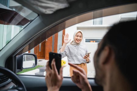 Foto de Veiled woman waves to an online transportation driver when he comes to pick her up - Imagen libre de derechos