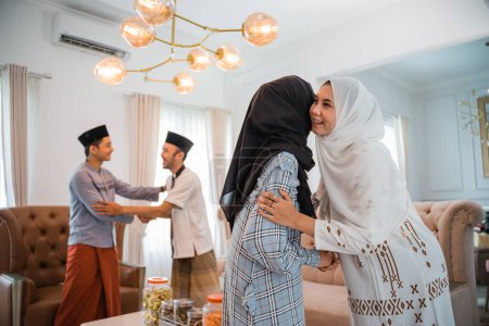 Foto de Dos mujeres en hiyab abrazando durante la visita de la familia eid celebración en casa - Imagen libre de derechos