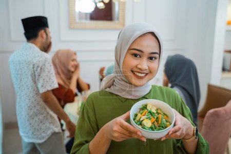 Téléchargez les photos : Belle femme musulmane avec de la nourriture servie pour la famille et l'ami pour le dîner ensemble - en image libre de droit