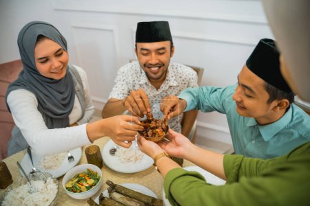 three Muslims take dates served in a bowl when breaking the fast at home