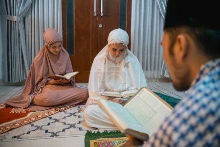 Photo for Female participants wearing hijab reciting the Quran following the male recitation leader at home - Royalty Free Image