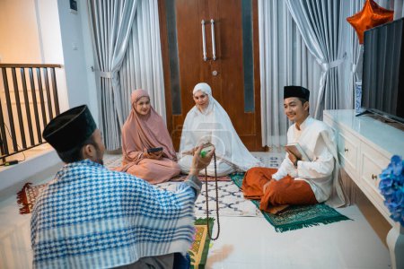 Photo for Recitation leader called kyai chats with recitation participants while reciting the Quran at home - Royalty Free Image