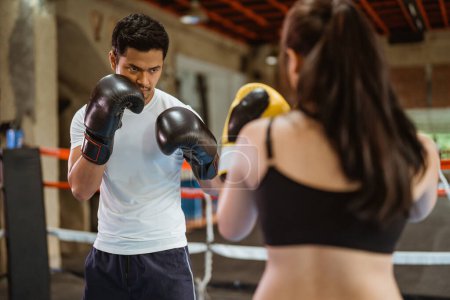 Téléchargez les photos : Le boxeur masculin combattant avec le boxeur féminin à l'intérieur de l'anneau de la boîte au studio de boxe - en image libre de droit