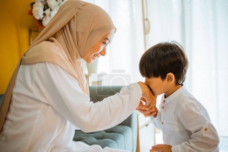 cute Asian boy kisses his mothers hand, salim is a tradition of respect for parents in Indonesia
