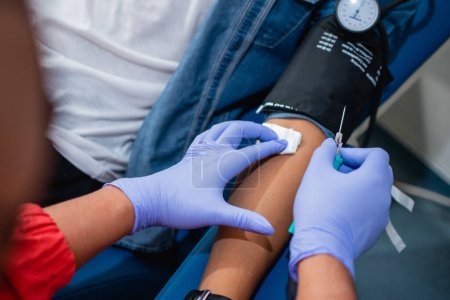 Téléchargez les photos : Le bras des donneurs est nettoyé avec du coton stérile avant l'aiguille pour transfusion sanguine - en image libre de droit