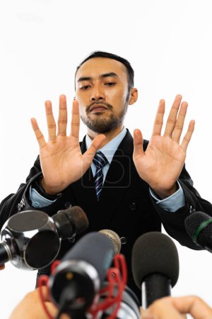 Téléchargez les photos : Un homme adulte en chemise bleue et costume noir avec cravate marine esquivée alors qu'offerte par beaucoup de microphone lors de la convergence de la presse - en image libre de droit
