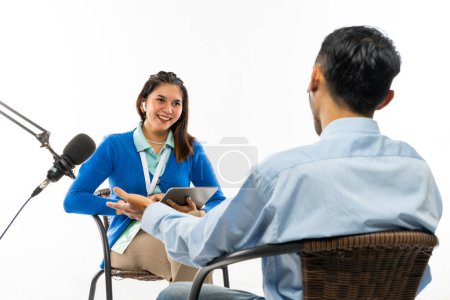 Foto de Una hermosa periodista en cárdigan azul sonriendo mientras hace una entrevista con el hombre adulto en camisa azul - Imagen libre de derechos