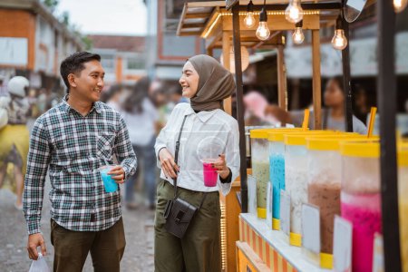 Téléchargez les photos : Portrait de heureux jeune couple musulman acheter à boire à un vendeur de rue - en image libre de droit