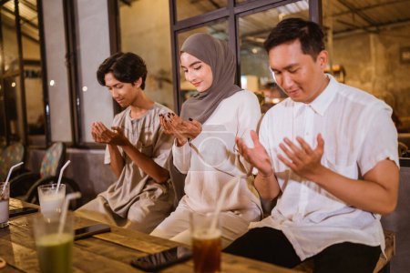 Téléchargez les photos : Musulmans asiatiques célébrant l'Aïd Moubarak prient avant de manger pendant un repas communautaire en plein air - en image libre de droit