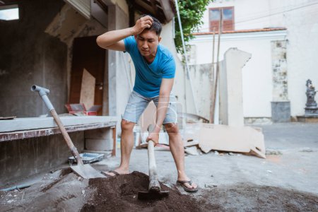Photo for Man gets headache while working on cement mixture using a hoe to build a house - Royalty Free Image