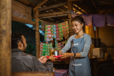 Foto de Camarera femenina con un delantal sirve comida y bebidas a los clientes en un puesto tradicional - Imagen libre de derechos