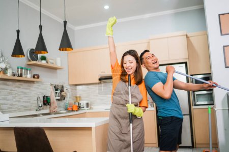 Téléchargez les photos : Asiatique couple avoir amusant tandis que nettoyage l 'maison ensemble - en image libre de droit