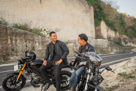 Téléchargez les photos : Cavaliers indonésiens veste assis sur la moto passer du temps ensemble - en image libre de droit