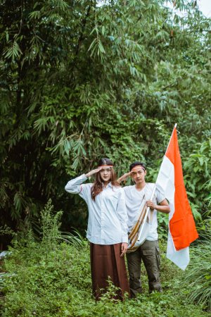 Téléchargez les photos : Un bel homme avec sarong et une belle femme en chemise blanche debout avec la salutation avec la nature comme arrière-plan - en image libre de droit