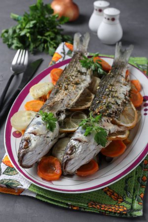 Foto de Salmonete al horno con verduras, especias y limón servido en un plato, Imagen vertical - Imagen libre de derechos
