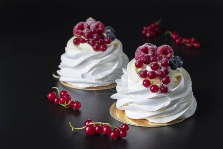Téléchargez les photos : Mini Pavlova cake with raspberry, blueberry and red currant on black background - en image libre de droit
