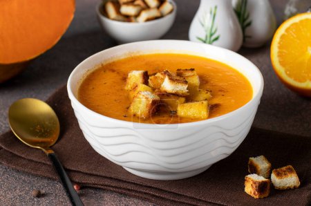 Photo for Pumpkin puree soup with orange, served in a white bowl with croutons - Royalty Free Image