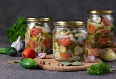 Téléchargez les photos : Salade de concombres marinés aux tomates et poivrons doux en trois pots sur fond gris foncé - en image libre de droit