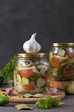Téléchargez les photos : Salade de concombres marinés aux tomates et poivrons doux en deux pots sur fond gris, image verticale - en image libre de droit
