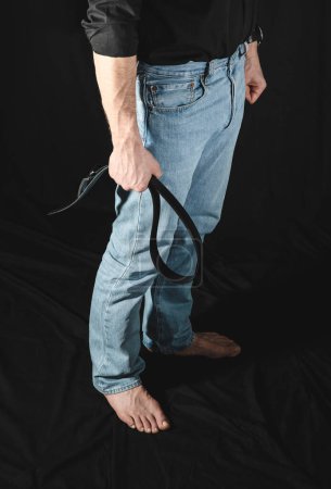 Strenger Mann mit Ledergürtel.. BDSM-Konzept. Schwarze Bäckerei