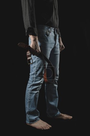 Strict man with leather belt.. BDSM concept. Black bakgrounde