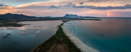 Photo for San Teodoro sand beach with lagoon, mountain of island Tavolara and coastline in Sadinia Italy from above during sunset, clouds and rainbow in sky - Royalty Free Image