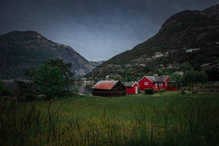 Téléchargez les photos : Red houses at the waterfront of small town of Eidfjord in Norway, surrounded by mountains of the fjord - en image libre de droit