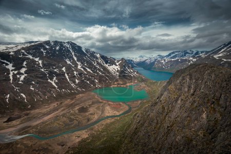 Téléchargez les photos : Turquoise and blue lakes in mountain landscape from above the hike to Knutshoe summit in Jotunheimen National Park in Norway, mountains of Besseggen in background, cloudy sky - en image libre de droit