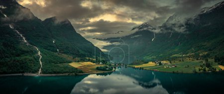Téléchargez les photos : Aerial view of landscape panorama of fjord at Briksdalsbreen glacier in Jostedalsbreen mountains during summer sunset, clouds in sky - en image libre de droit